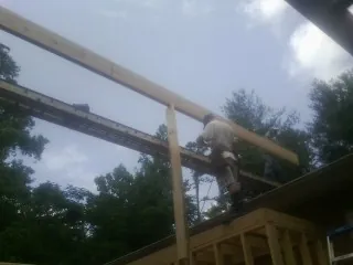 Carpenter setting a ridge beam over a new addition frame — Ice Dam Removal by Roofing Brothers in Fowlerville