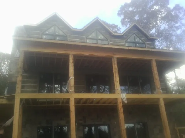 Dormers and porch framing on a large log home under construction — Roof Coating work by our crew in Fowlerville