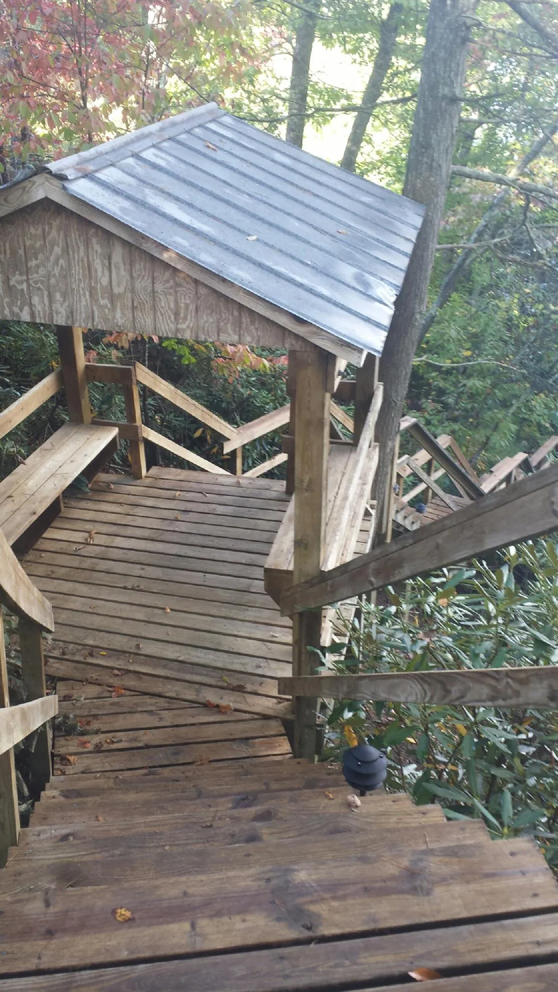Metal roofed shelter over wooden steps on a wooded walkway — Skylight Repair & Installation work by our crew in Fowlerville