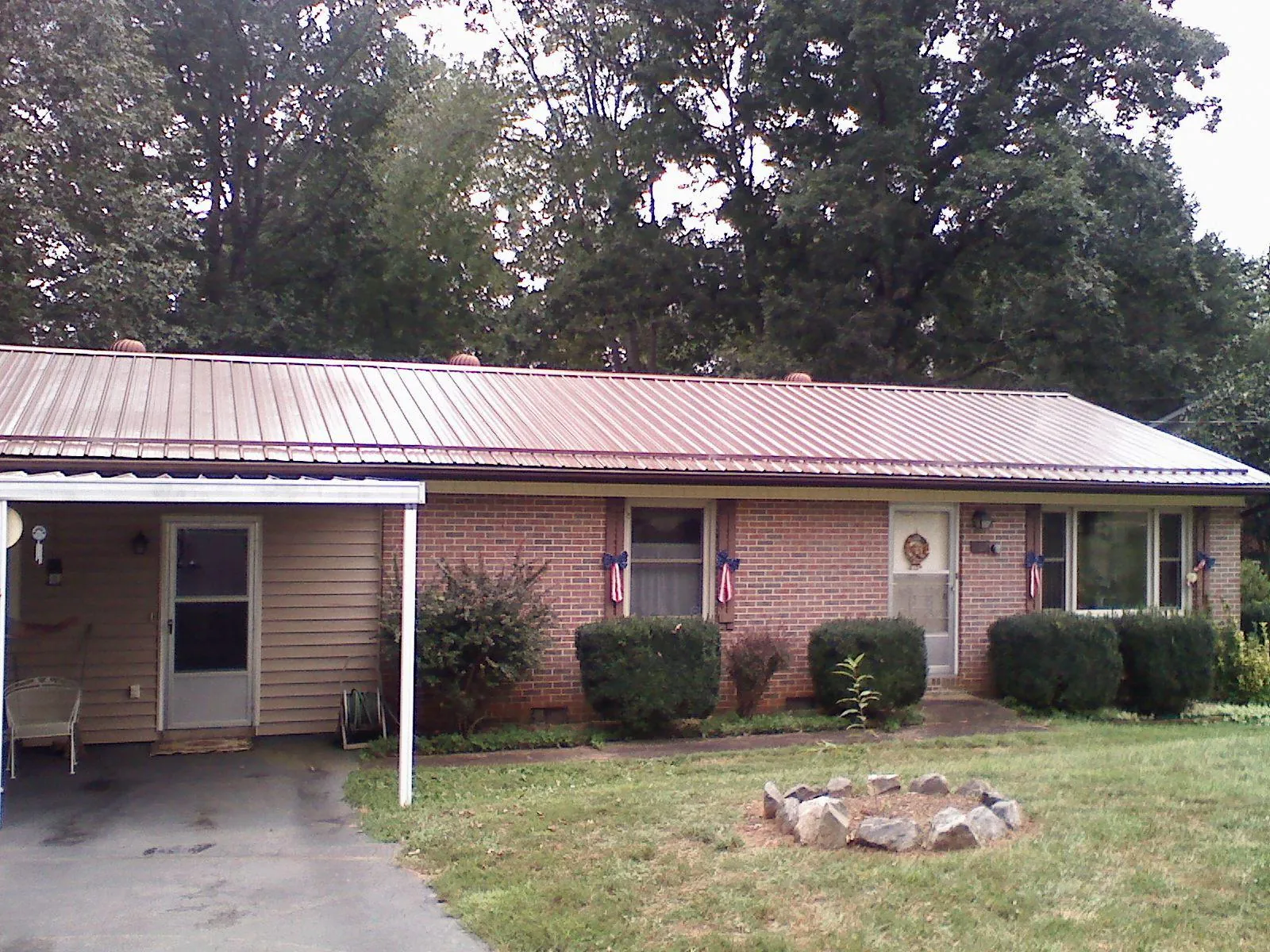 Bronze metal roof and carport on a brick ranch home — Roof Repair work by our crew in Fowlerville